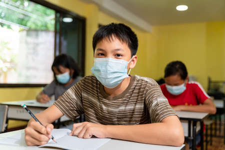 Happy asian boy with face mask back at school after   quarantine and lockdown.の写真素材