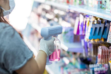 staff wearing gloves using portable usb nano sanitizer spray disinfectant machine fogger for covid19 in the shopの写真素材