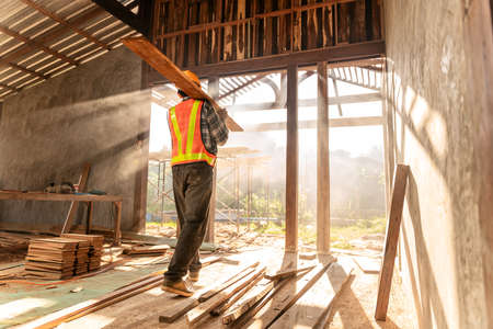 Carpenter holds wooden planks on construction siteの写真素材