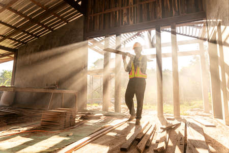 A carpenter holds wooden planks on construction siteの写真素材
