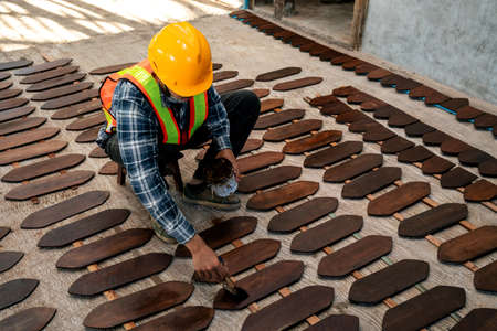 Worker painting or varnish on wooden board on construction site.の写真素材