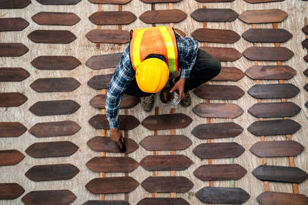 Top view of craftsman or paintbrush applies paint or varnish on wooden board on construction site.の写真素材