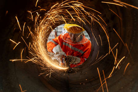 An Electric wheel grinding at Industrial worker cutting metal pipe with many sharp sparksの写真素材