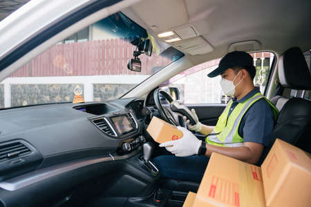A delivery man using a credit card reader. In the van with parcels on the outside of the warehouse. Deliveryの写真素材