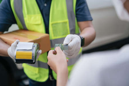 Close up hand of delivery man accept credit card using a credit card reader while delivering...