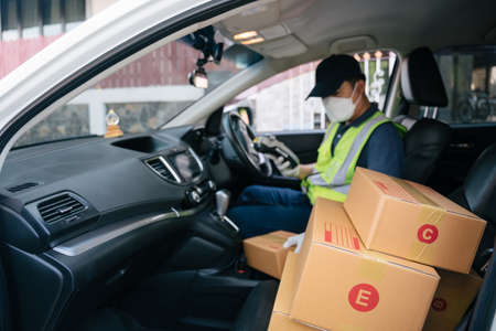 Select focus a box, A delivery man using a credit card reader. In the van with parcels on the outside of the warehouse. Deliveryの写真素材