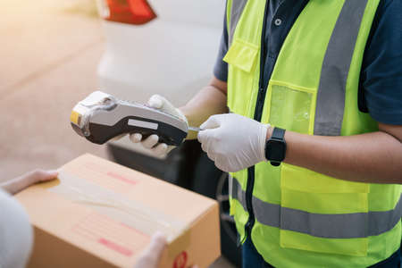 Close up hand of delivery man using a credit card reader while delivering products to customers at home, Cash on delivery concept with credit card.の写真素材