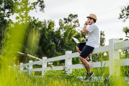 A male freelancer making telephone call share good news about project working in nature, Male adventure bloggerの写真素材