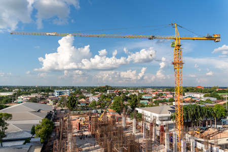 A crane in large construction site, Crane working on a building complex with cloud and blue sky.