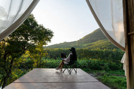 Freelancer woman working on laptop during vacation holidays in summer among the trees and mountains. female blogger.の写真素材