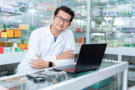 A male pharmacist use a laptop in a drugstore, Medical healthcare concept.の写真素材