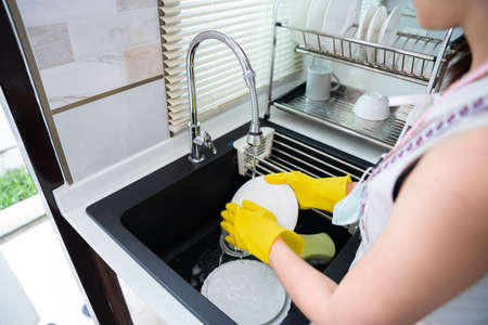 Attractive hands of woman is washing dishes while doing cleaning in the kitchen sink, maidの写真素材