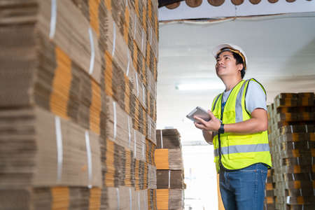 Warehouse worker courier inspecting checklist stock cardboard boxes for sale.の写真素材
