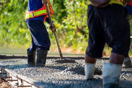 Pouring wet concrete while paving a driveway at road construction siteの写真素材