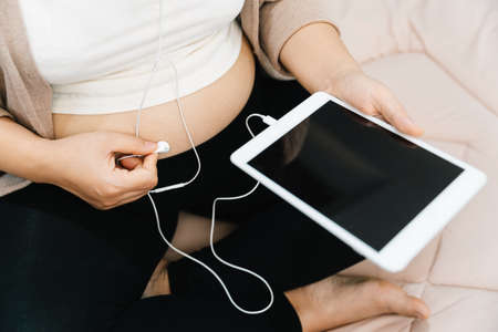 A Pregnant woman listening to music with a tabletの写真素材