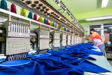 A worker working with sewing machine, Embroidery area in textile factory in industrial zone with modern machinery and technology systems. select focus of sewing machine.の写真素材
