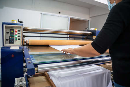 A worker printing on t shirt in workshop. clothing industry concept. Heat transfer machine.の写真素材