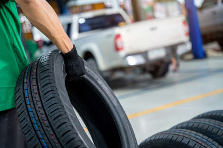 Close up hand of Auto Mechanic holding new tire in Car repair station.の写真素材