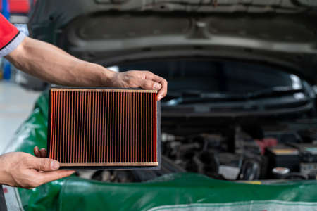 Auto mechanic is checking the engine filter in Car repair station.