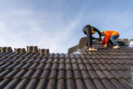 2 Roofers worker in protective uniform wear and gloves, using air or pneumatic nail gun and...