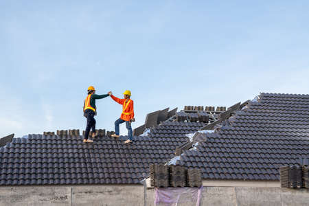 Teamwork of A Construction worker install new roof, Electric drill used on new roofs with Concrete Roof Tiles, Roofing tools.の写真素材