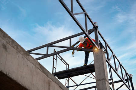 A Welders on risk areas. Steel roof truss welders are working on the roof structure with safety...