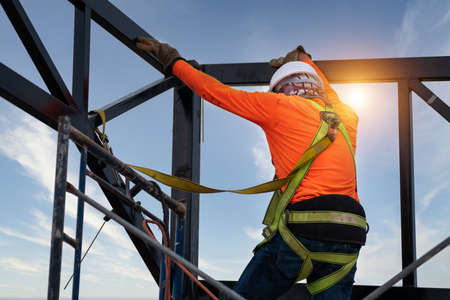 A Construction workers wear safety equipment to prevent falls from heights or Fall arrestor device for worker with hooks for safety body harness on the construction site.の写真素材