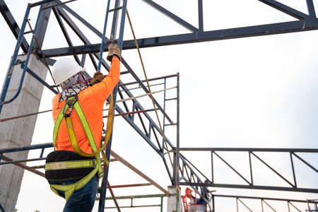 Construction workers are working on steel roof trusses with Fall arrestor device for worker with hooks for safety body harness on the construction site.の写真素材