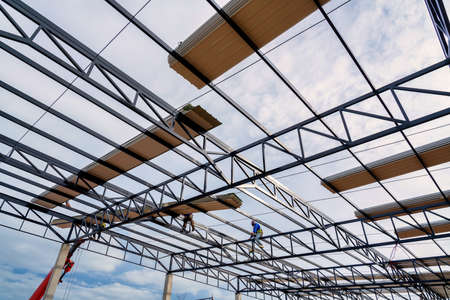 PU foam roof sheet on steel roof structure Along with construction workers and cranes are lifting the PU foam roof sheet to install on the steel roof structure at the construction site.の写真素材