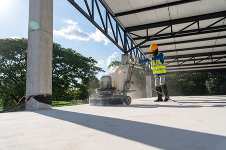 Construction worker produces the grout and finish wet concrete with a special tool at construction site. Concrete surface sanding machine. Concrete floors.の写真素材