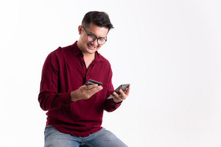 Asian man using mobile phone with credit card in studio white isolated background. Online buying and selling concept and pay by credit card.の写真素材