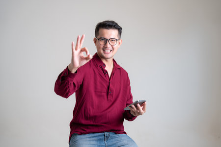 Asian man feel great using mobile phone with credit card in studio white isolated background. Online buying and selling concept and pay by credit card.の写真素材