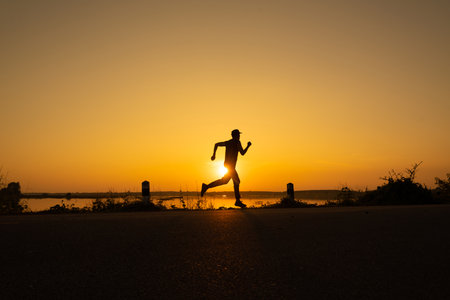 Athletic runner start training on fitness tracker or smart watch and looking forward near sunset. Trail running and active lifestyle concept. silhouette photo.の写真素材