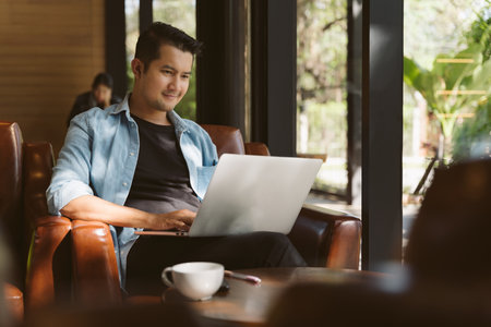 A freelancer bearded man in t-shirt taking notes at laptop in cafe. Freelance and remote work. Concept of freelance and financial freedom.の写真素材