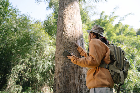 Asian young girl touching a tree in the wild forest. Traveler girl in a beautiful green forest. Nature conservation, environmental protection.の写真素材