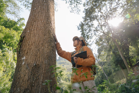 Asian young girl touching a tree in the wild forest. Forest ecology. Wild nature, wild life. Earth...
