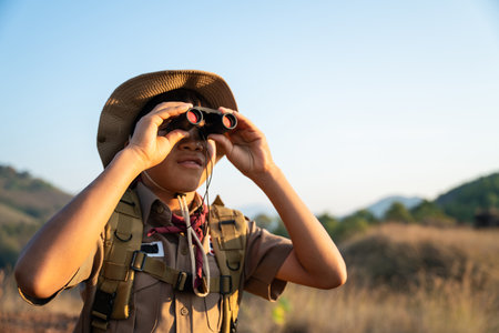 Asian Boy Scouts exploring nature with binoculars in camp on the mountain. landscape survey concept.の写真素材