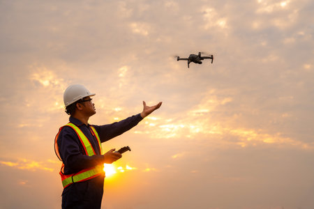 Asian surveyors or explorer deploying drones to view construction sites or check security at sunset.