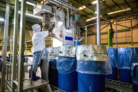 A worker controls an automatic aseptic filling machine filling ketchup into large drums at an industrial plant. food industry. Agriculture industry.の写真素材