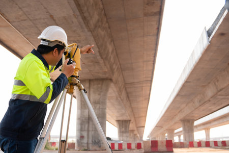 A male surveyor engineers worker making measuring under the expressway with theodolite on road works. Survey engineer at road construction site, Surveyor equipment.  Highway.の写真素材