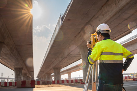 A male surveyor engineers worker use radio communication and making measuring with theodolite on road works. Survey engineer at road construction site, Surveyor equipment. Highway.の写真素材