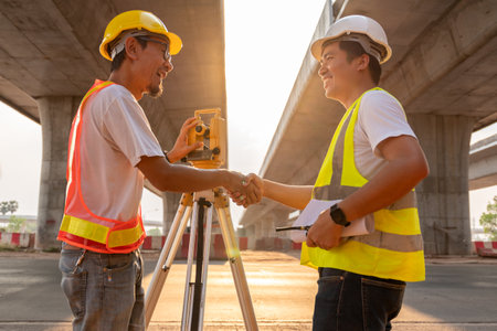 Asian civil engineer and surveyor engineers happily shake hands after work  at road construction site, Surveyor equipment. Highway.の写真素材
