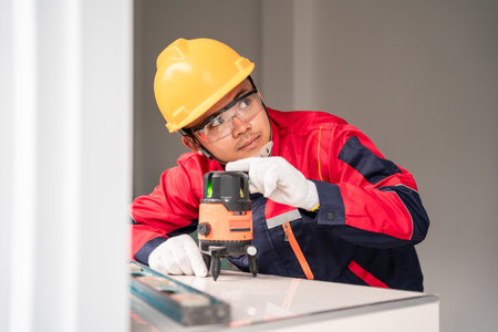 Asian engineer or construction worker is using laser level in building construction with green beam...