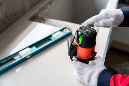 hands of engineer or construction worker using laser level instrument to measure the level inside...