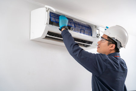 Air technician service removing air filter of the air conditioner for cleaning on white wall. Service concept of an air conditioner technician.の写真素材