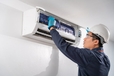 Air technician wear uniform service removing air filter of the air conditioner for cleaning on white wall. Service concept of an air conditioner technician.の写真素材