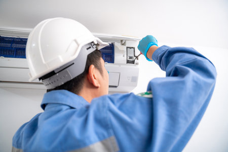 Close-up hand of Air technician service repairing and installs air conditioner on white wall. Service concept of an air conditioner technician.の写真素材