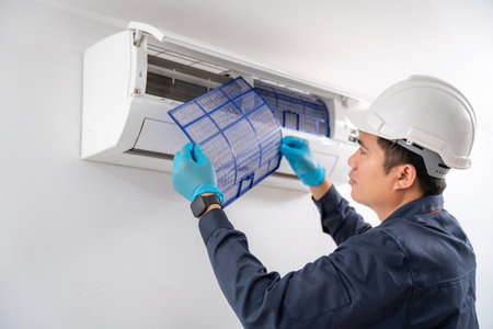 Air conditioner technician removes the air filter of the air conditioner to clean the dust of the air conditioner on the white wall. Service concept of an air conditioner technician.の写真素材