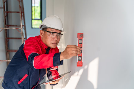 Asian engineer or inspector senior expert  is using the water level to inspect residential subdivision home building at construction site.の写真素材