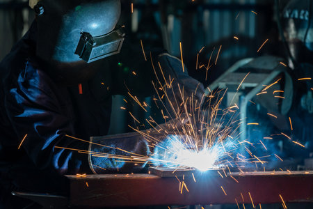 An employee or heavy industrial worker inside factory with industrial worker using welding machine. Industrial safety first concept.の写真素材